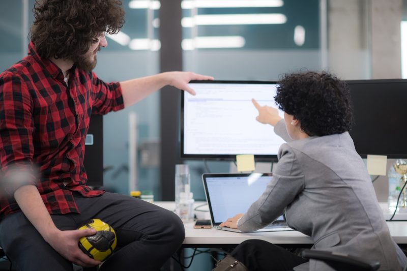 två personer framför en dataskärm och pekar på skärmen.